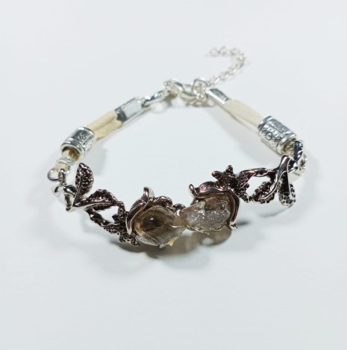 Bransoletka róże w kolorze starego srebra na jasnym rzemieniu
z kryształem górskim
Długość bransoletki 17 cm + 4 cm