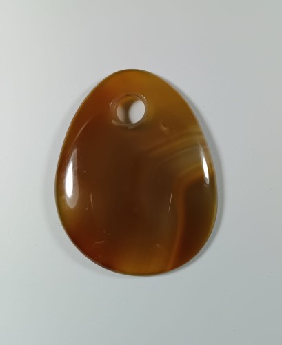 Agat z otworkiem na rzemień, w ciepłym, bursztynowym kolorze.